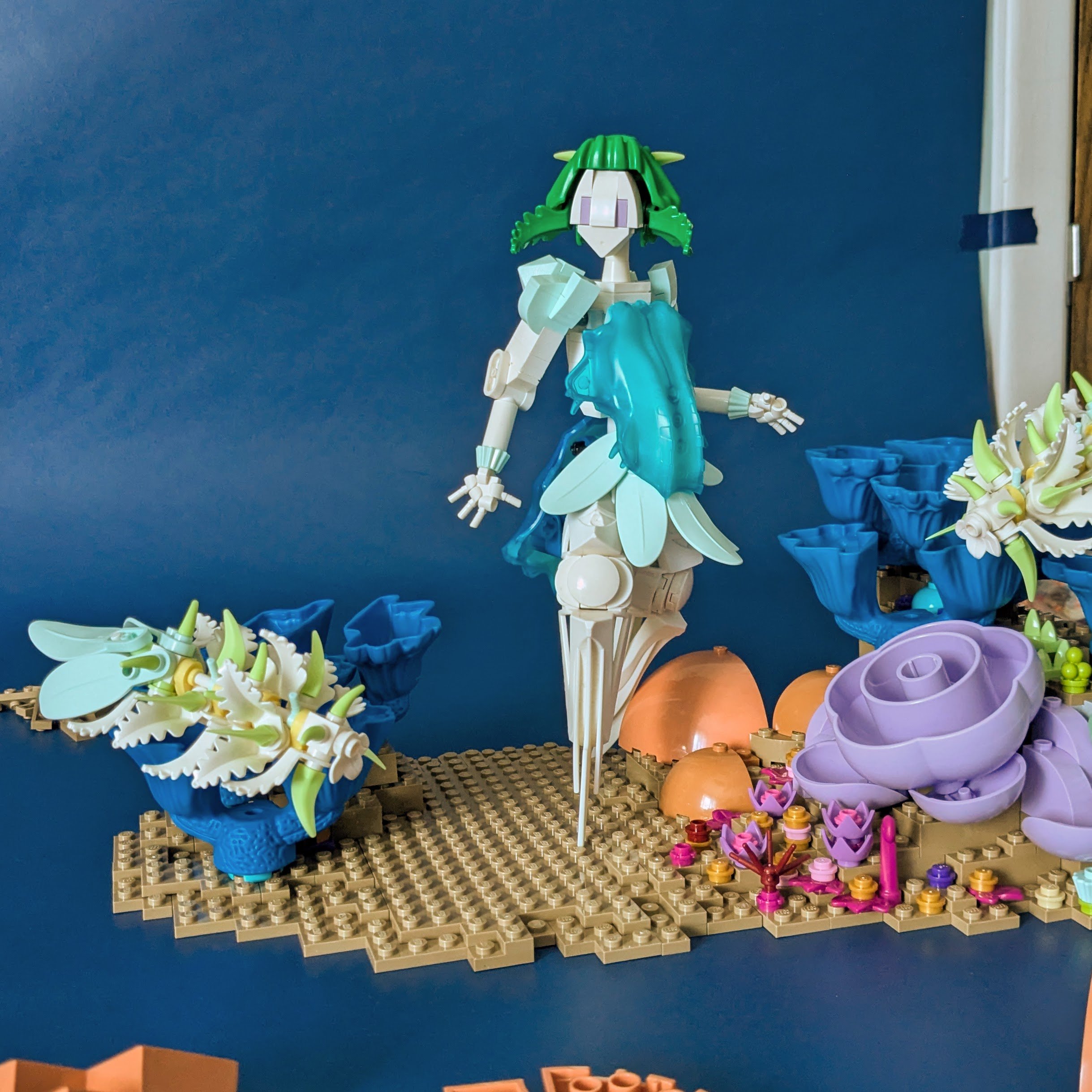 Figure on an unfinished seafloor base, one shin propped against a bulb of rock or coral