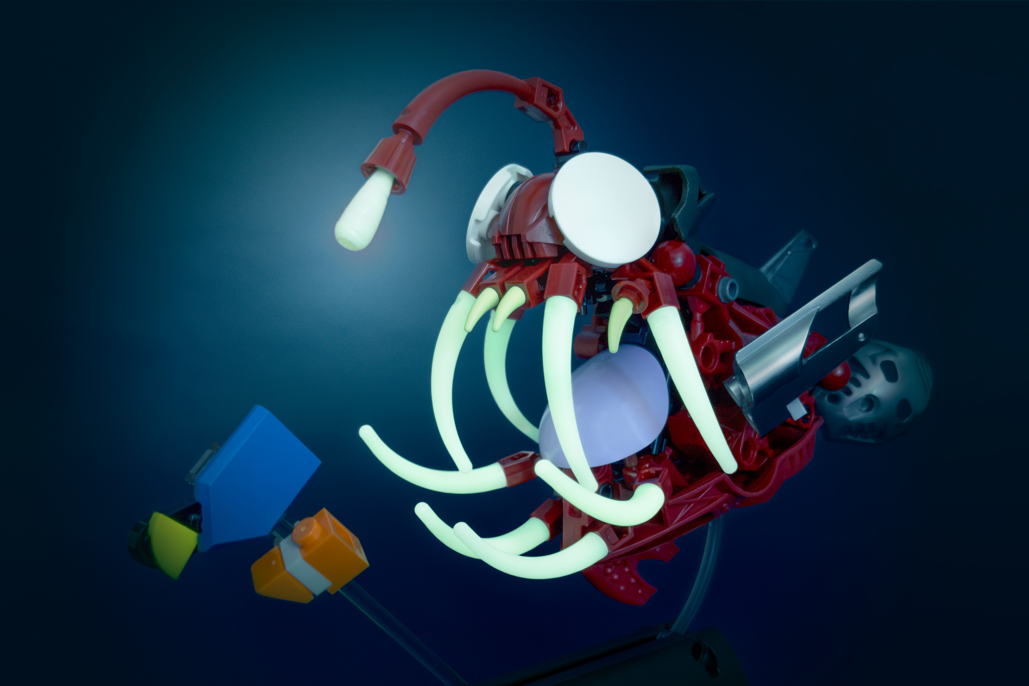 A simple clownfish and blue tang cower before a hulking anglerfish with blank eyes and needle-like teeth