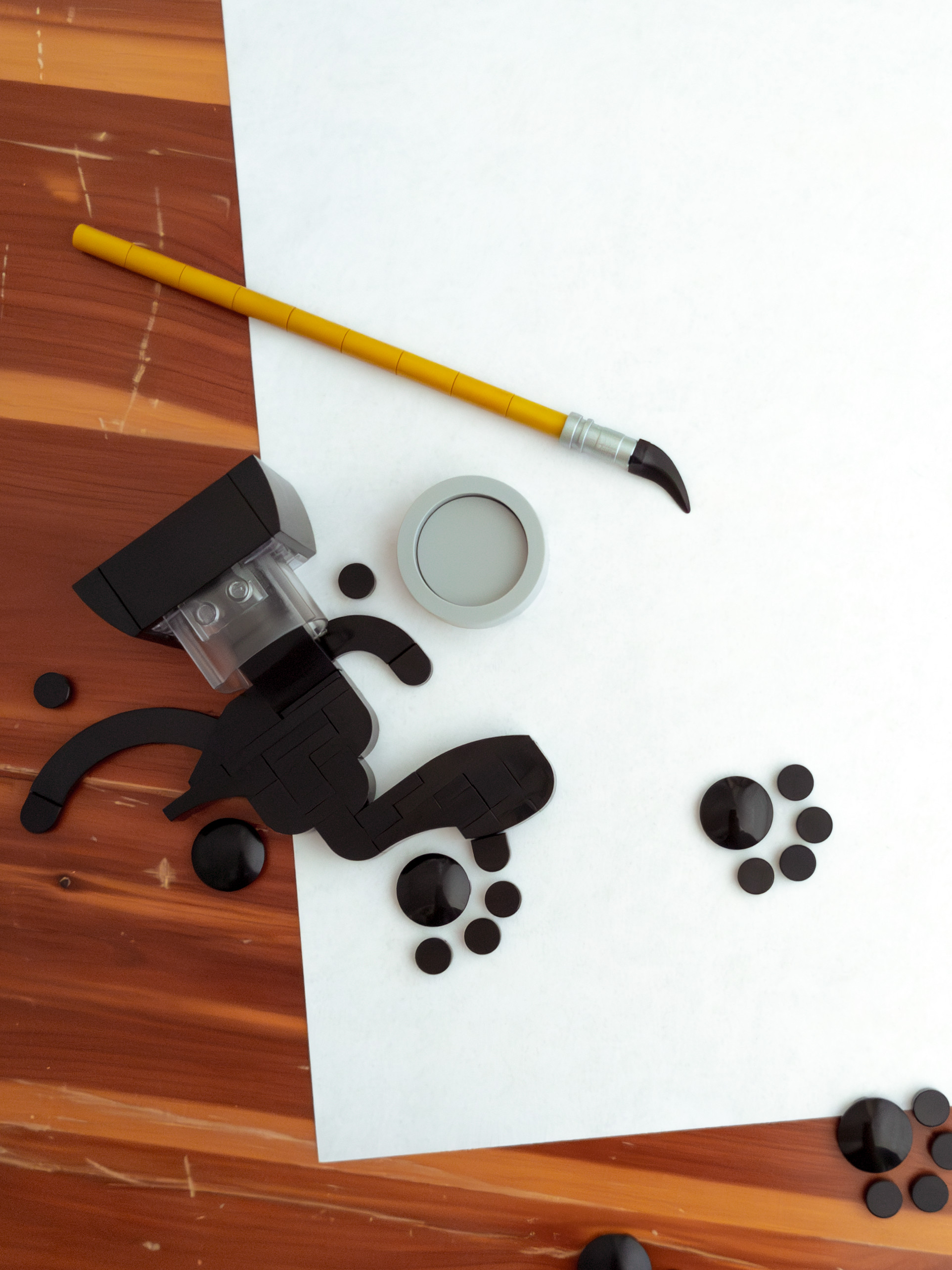 Spilled black ink on white paper; cat pawprints lead away from inkpot and brush