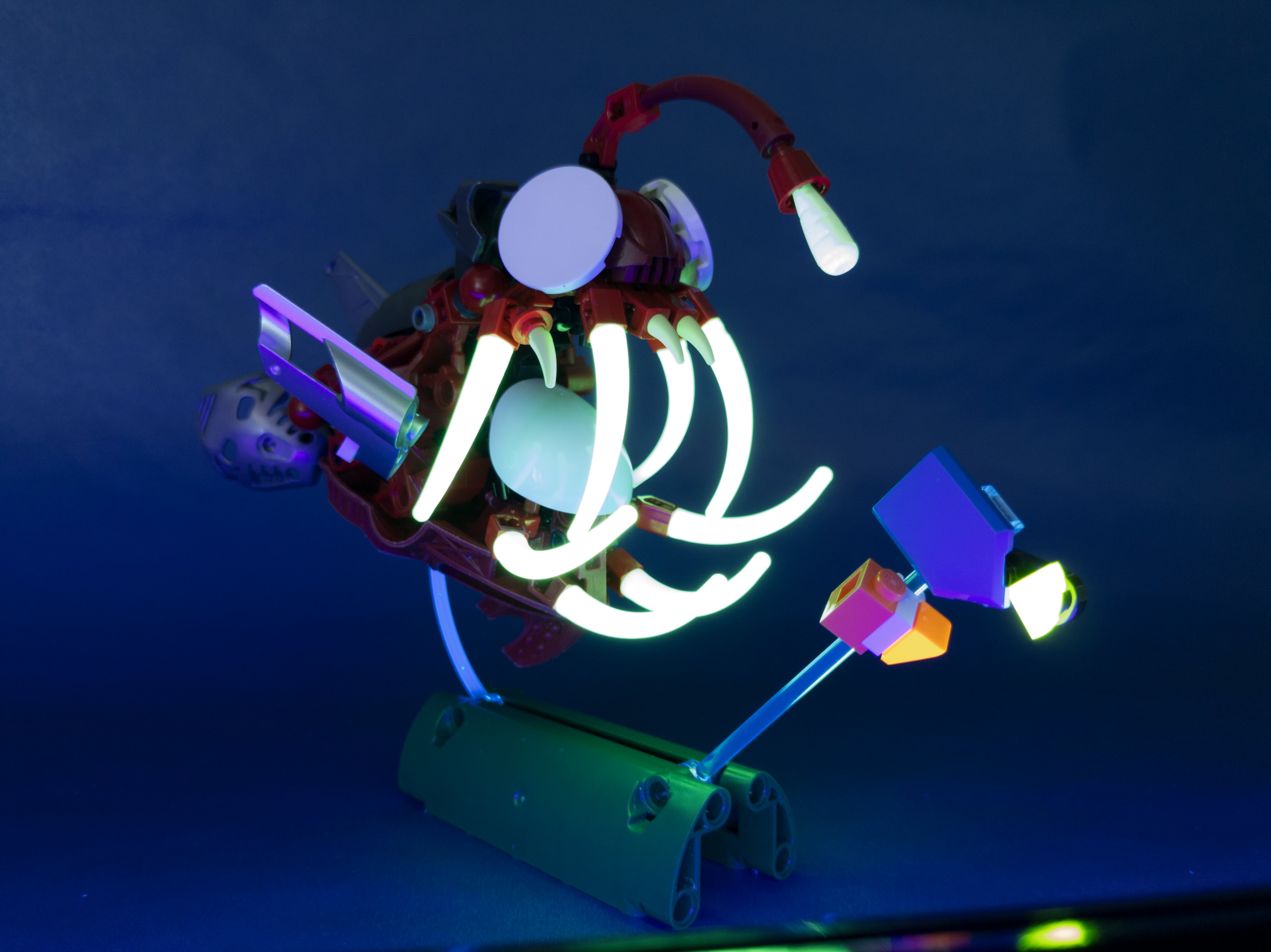 Harsh, green light emanates from anglerfish teeth and lure, casting shadows in a dark scene
