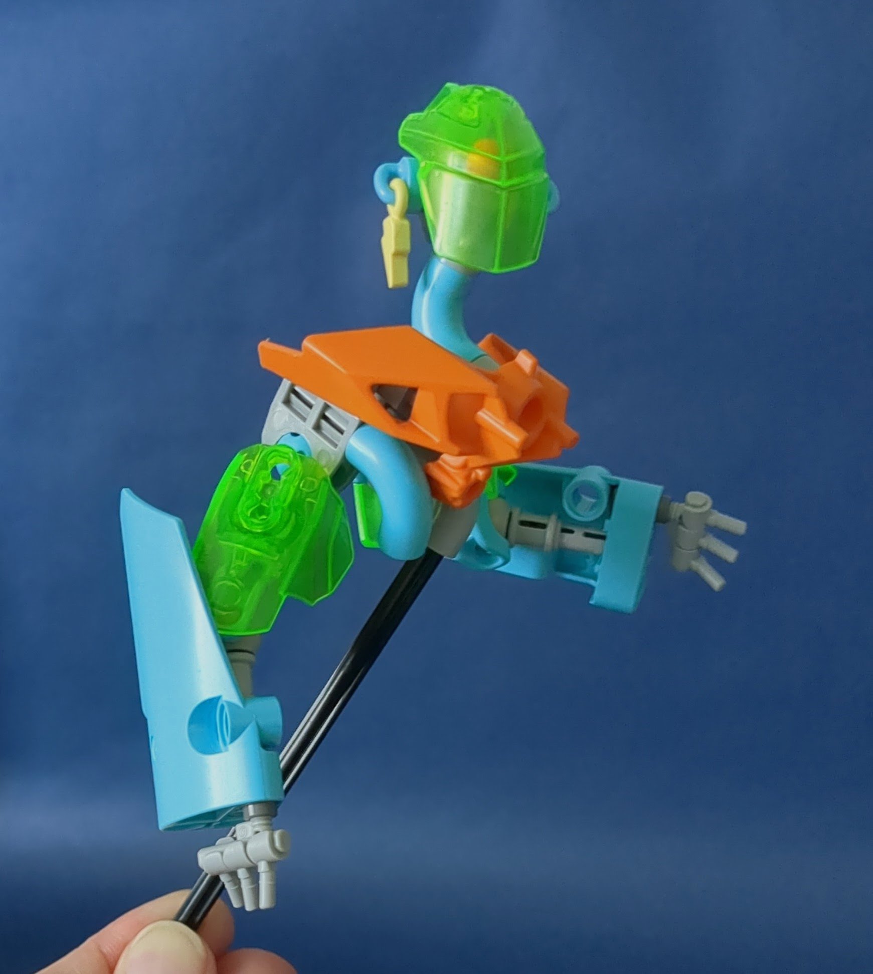 Upper torso and arms of a cybernetic character; base colors are azure and bright green, with angular orange accents