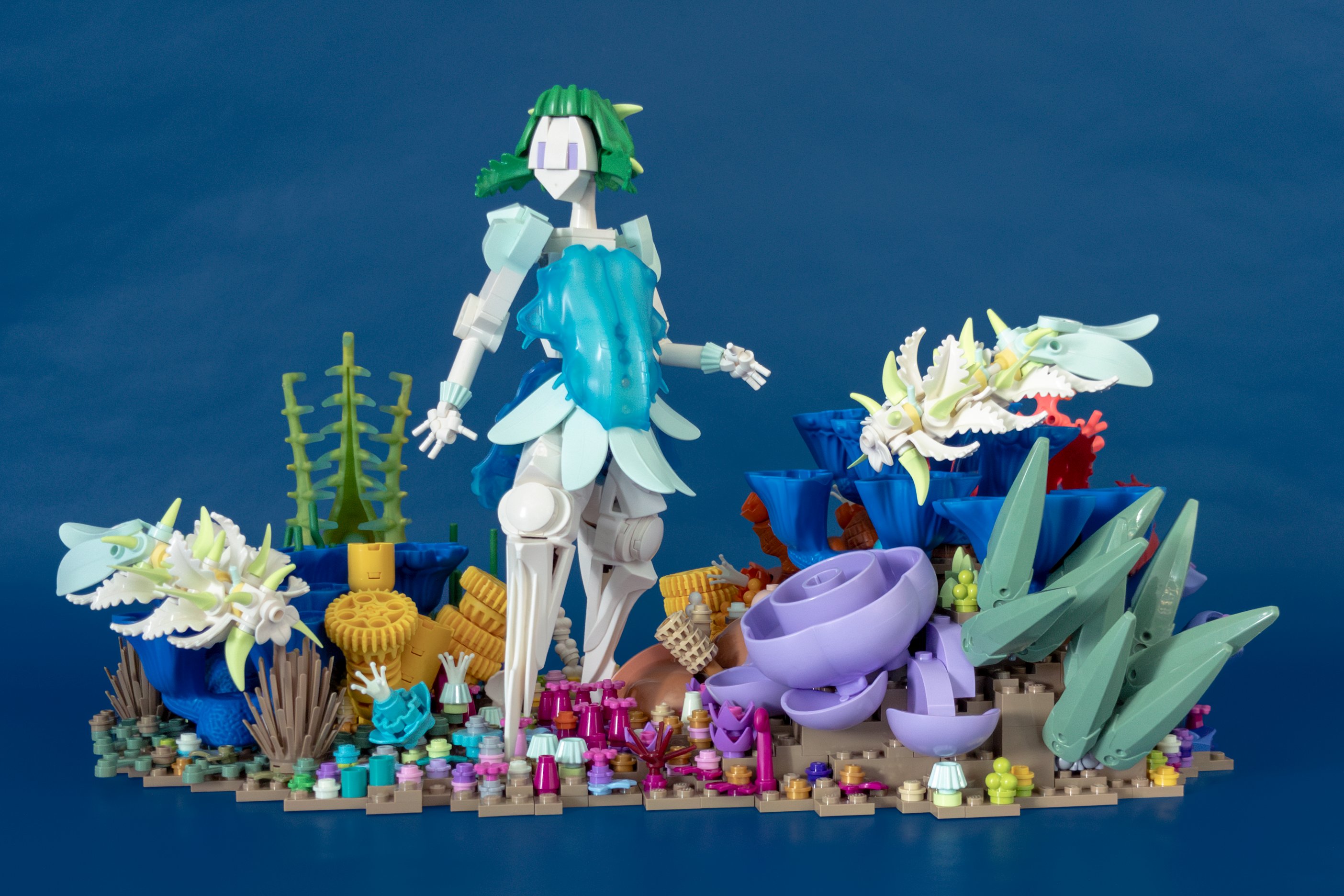 A small figure in a dress stands amid coral and sponges, with sea slugs swimming around her
